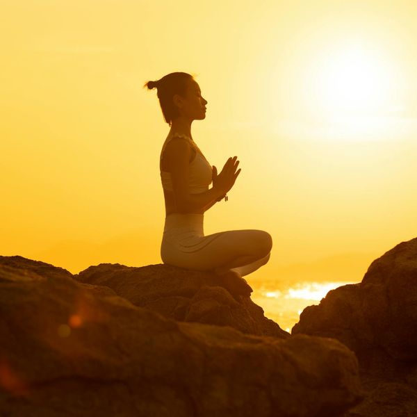 Silhouette of a person in a yoga pose against a sunset.