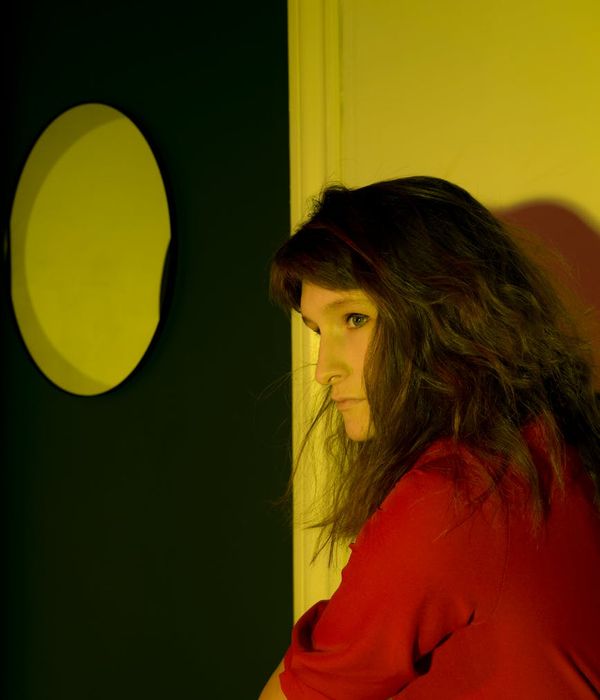 Woman in a calm yoga pose in a dark room with red ambient light.